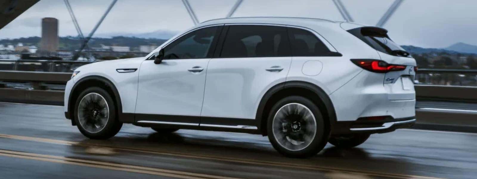 2026 Mazda CX-90 PHEV driving through a scenic outdoor setting