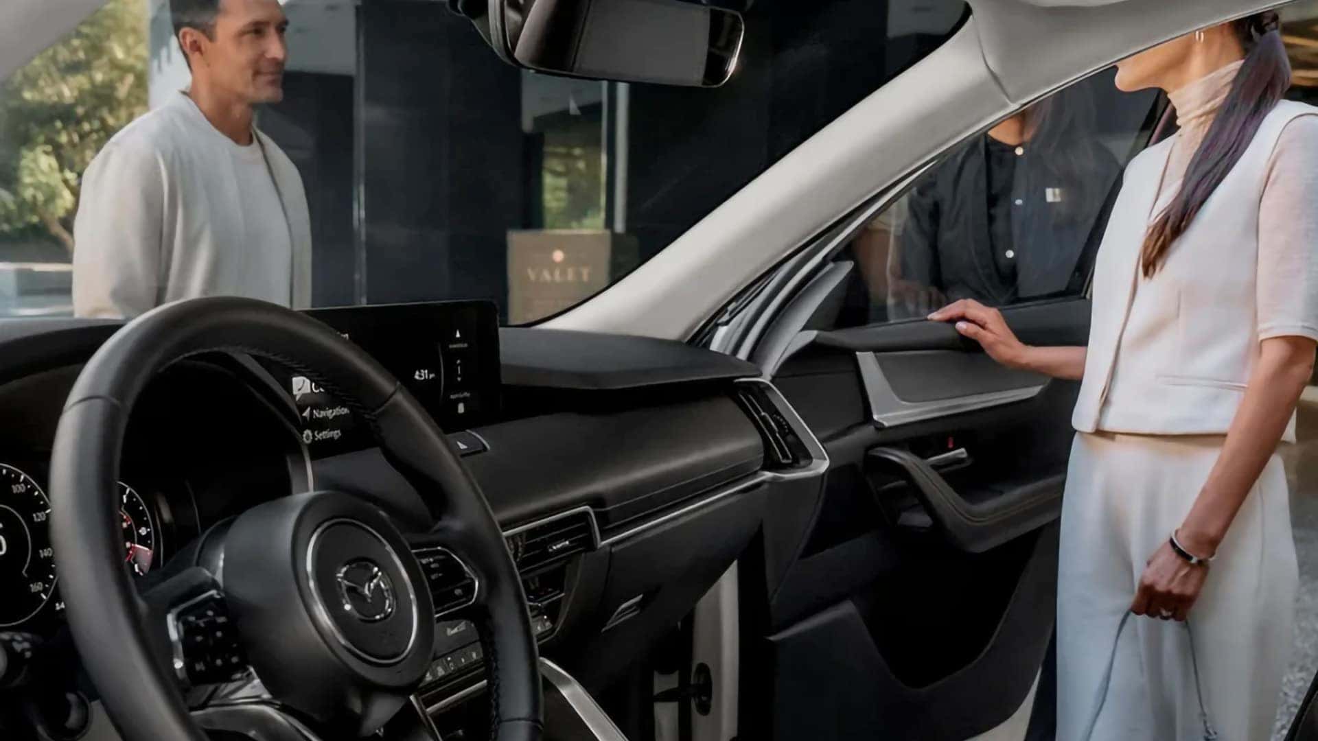 2026 Mazda CX-70 PHEV cockpit with steering wheel, infotainment display, and open driver door
