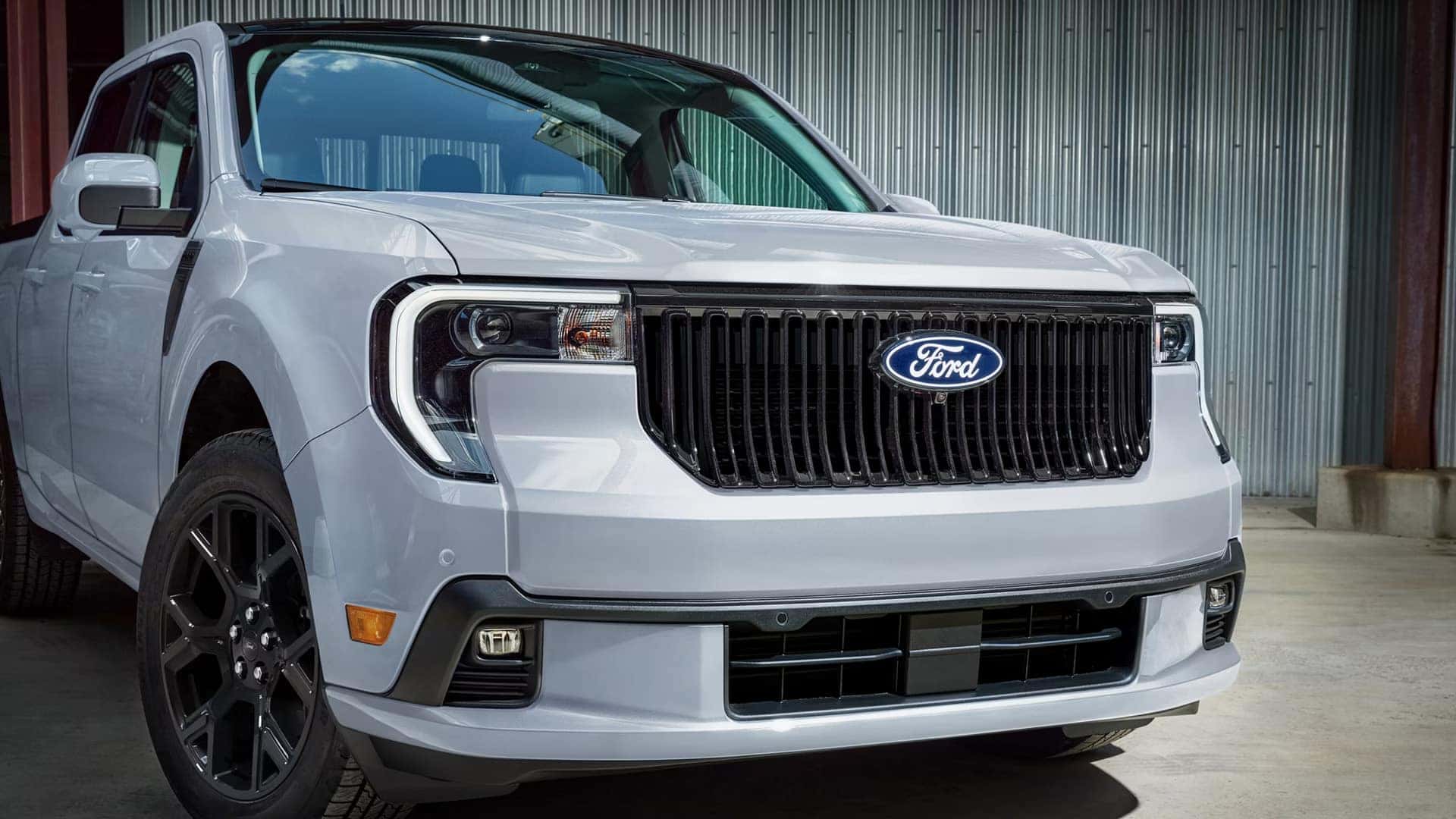 Close-up of a white 2026 Ford Maverick showing its black grille, Ford badge, and front lighting