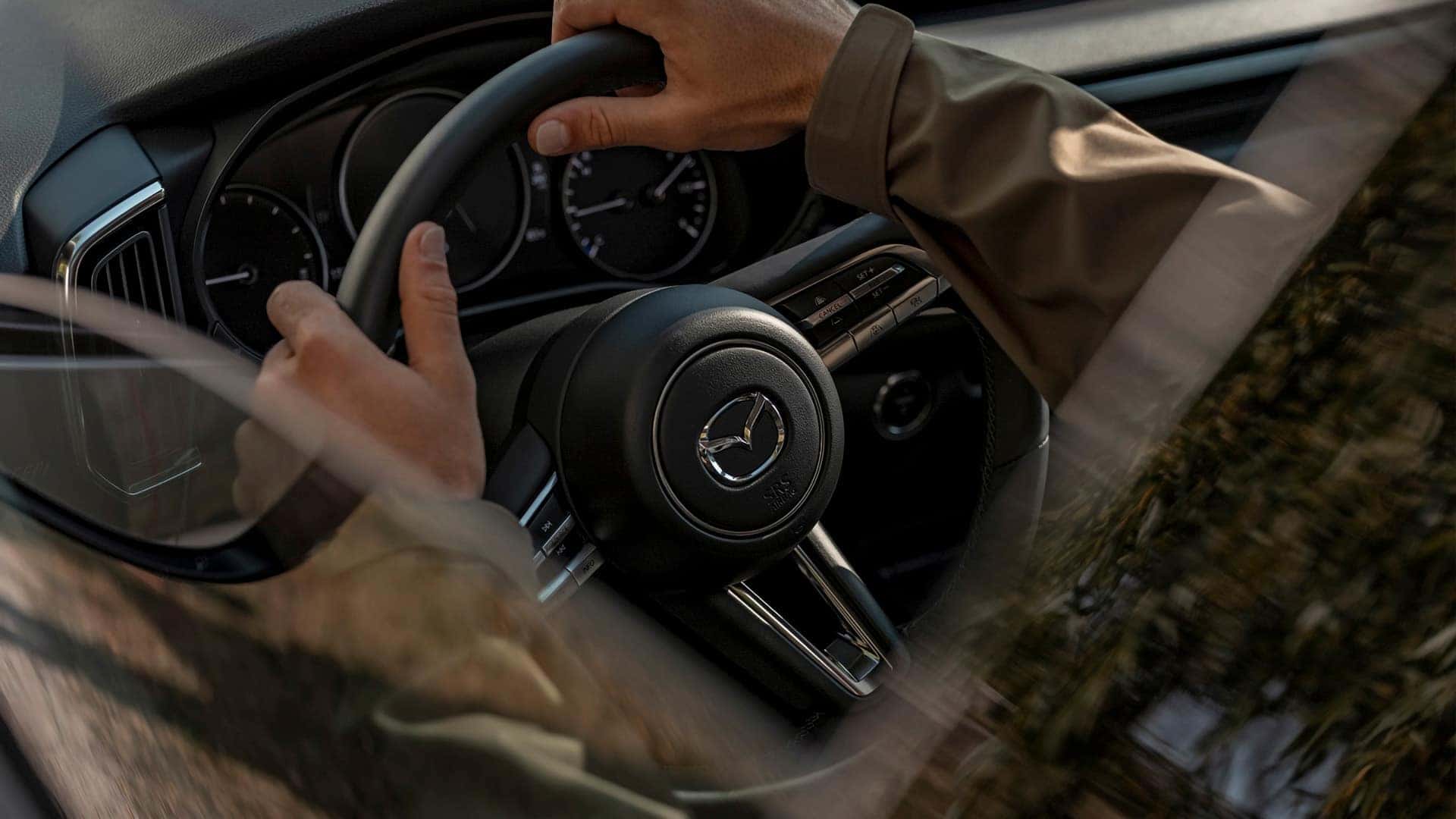 Driver holding the Mazda steering wheel inside the 2026 Mazda CX-50 Hybrid