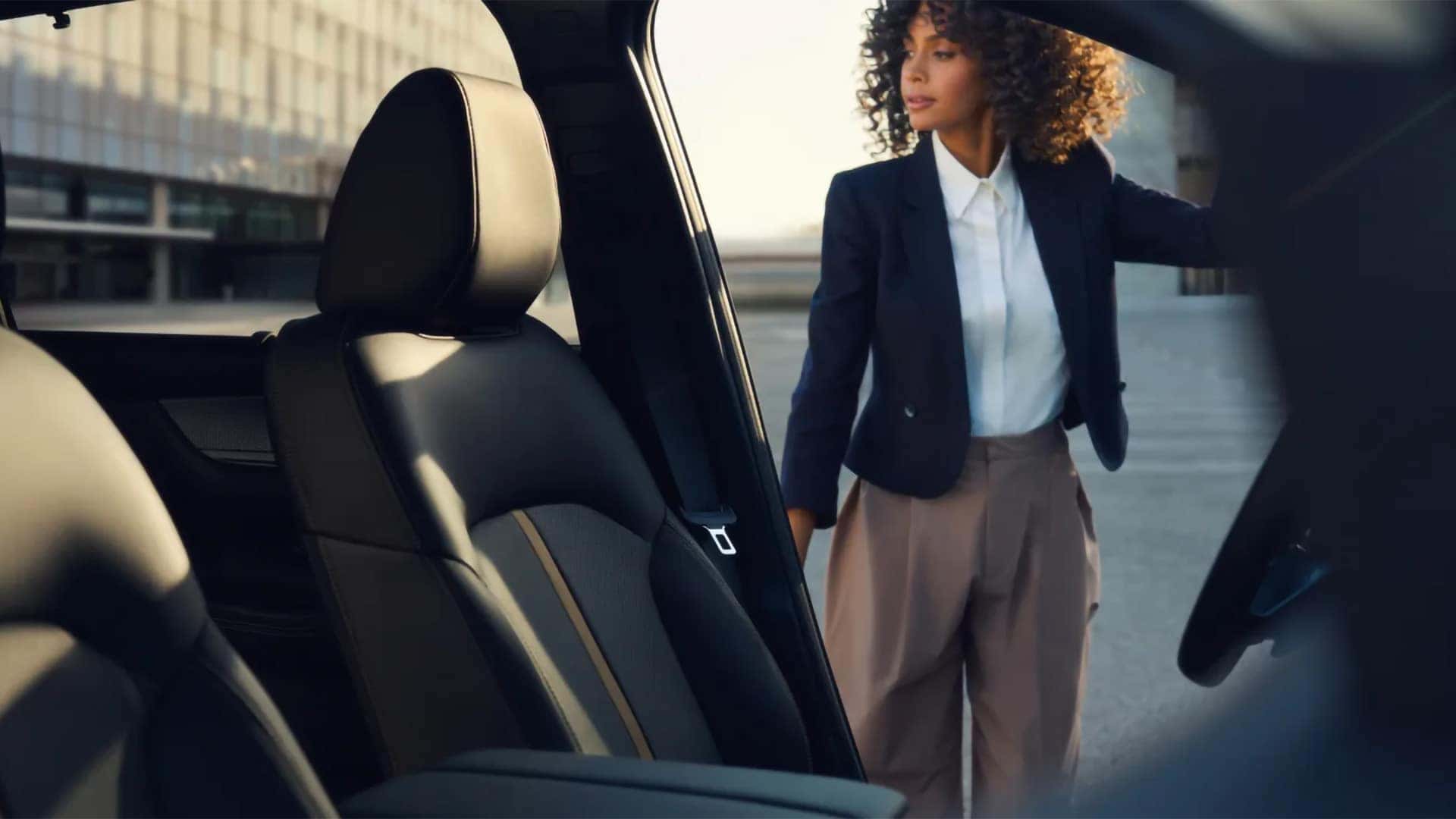 Woman opening the door of a 2026 Mazda CX-90 PHEV with black leather-trimmed seating