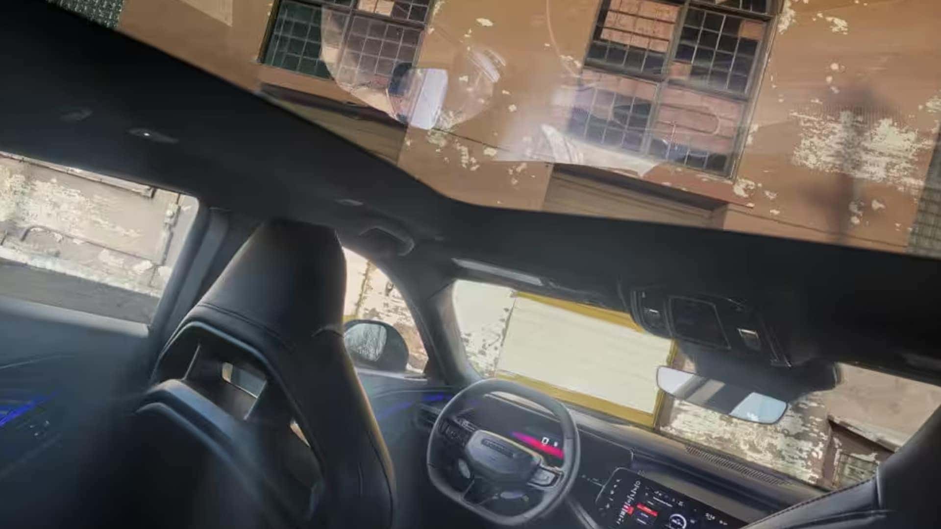 Interior view looking upward at a large glass roof panel above the front seats and dashboard.