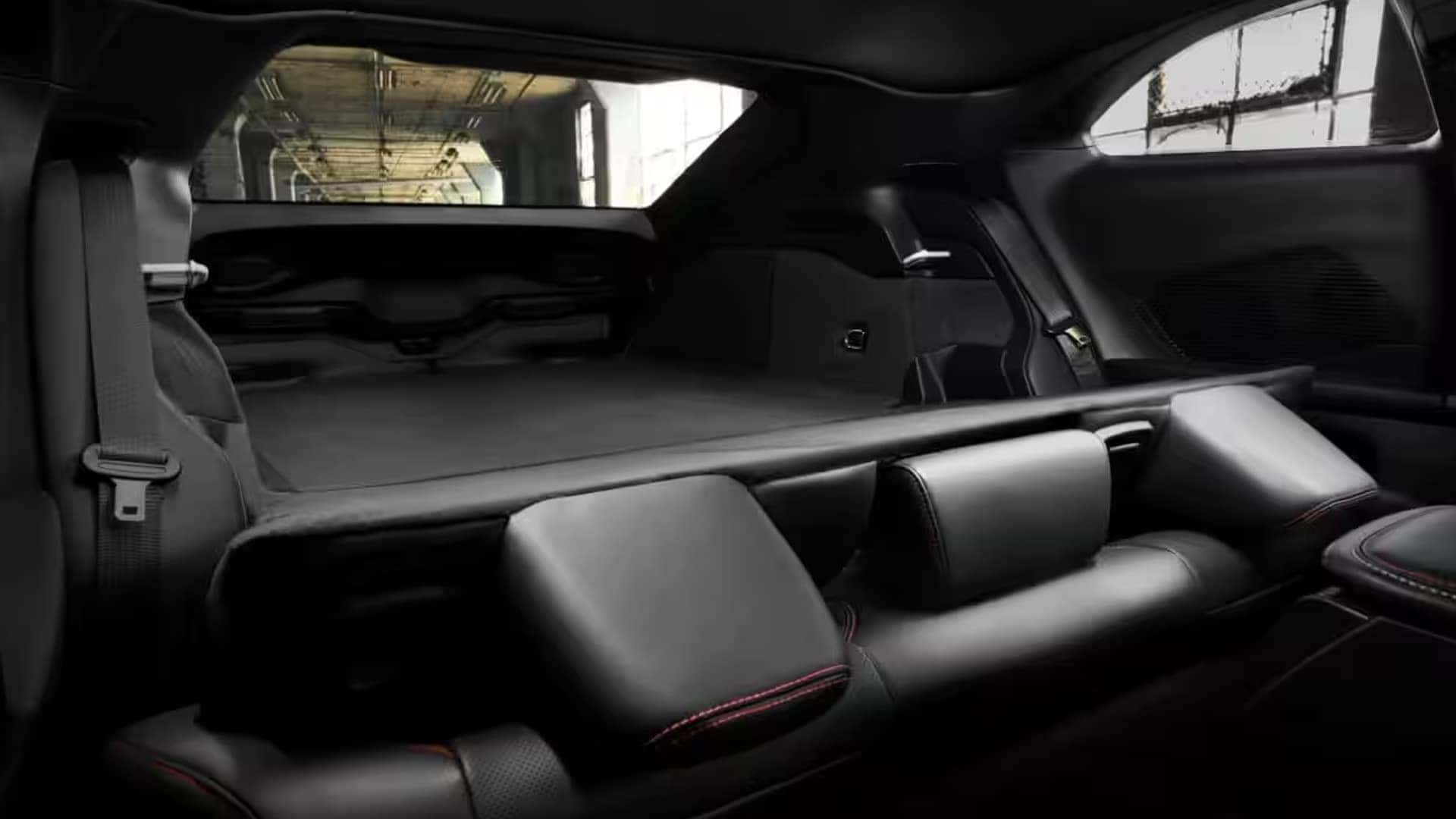 Rear cabin with black seats folded down to create a long, flat cargo area beneath the rear window.