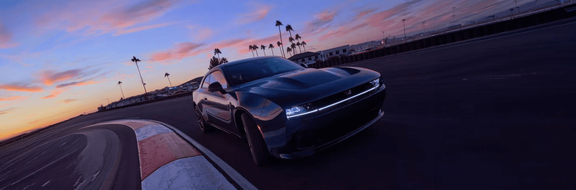 Dark two-door Dodge Charger shown driving around a track corner.