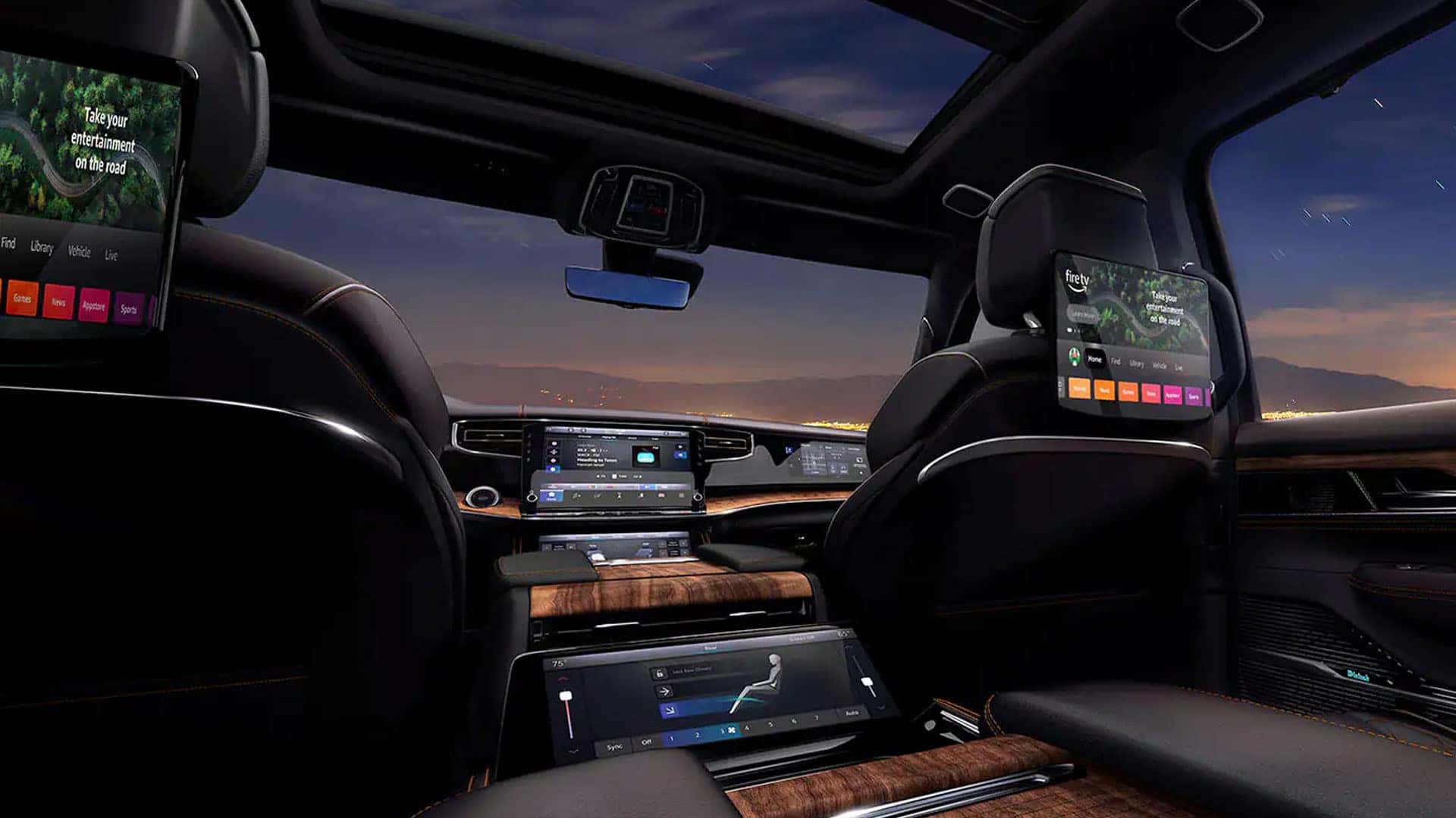 2026 Jeep Grand Wagoneer rear cabin with two seatback Fire TV screens, center display and panoramic glass roof.
