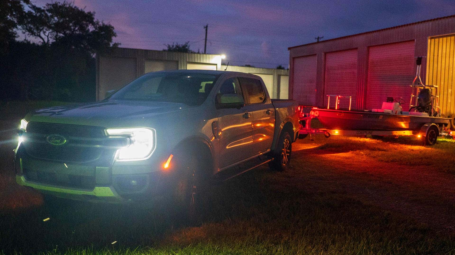 2026 Ford Ranger towing a boat at night with LED headlights and exterior lighting illuminated