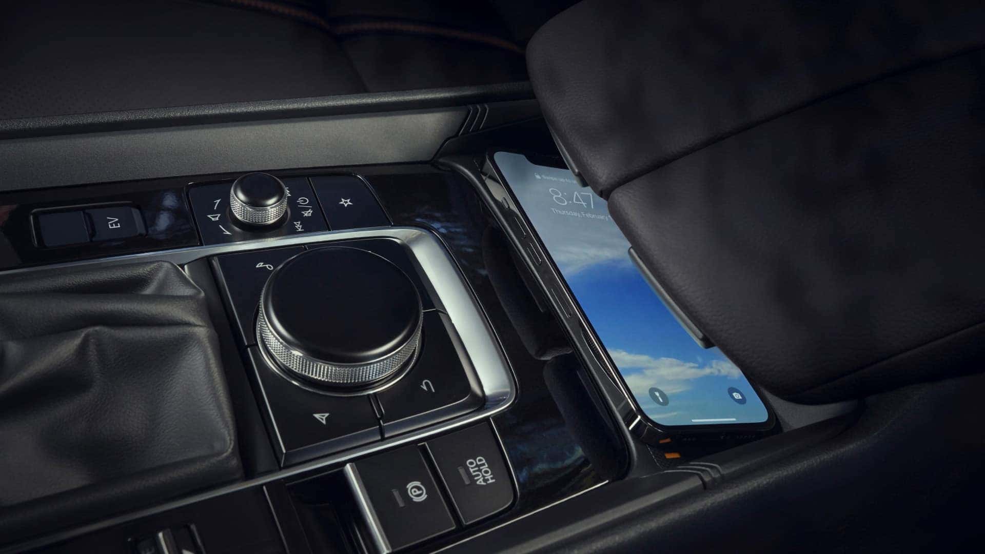 Smartphone charging beside the Mazda Connect Commander controls in the 2026 Mazda CX-50 Hybrid