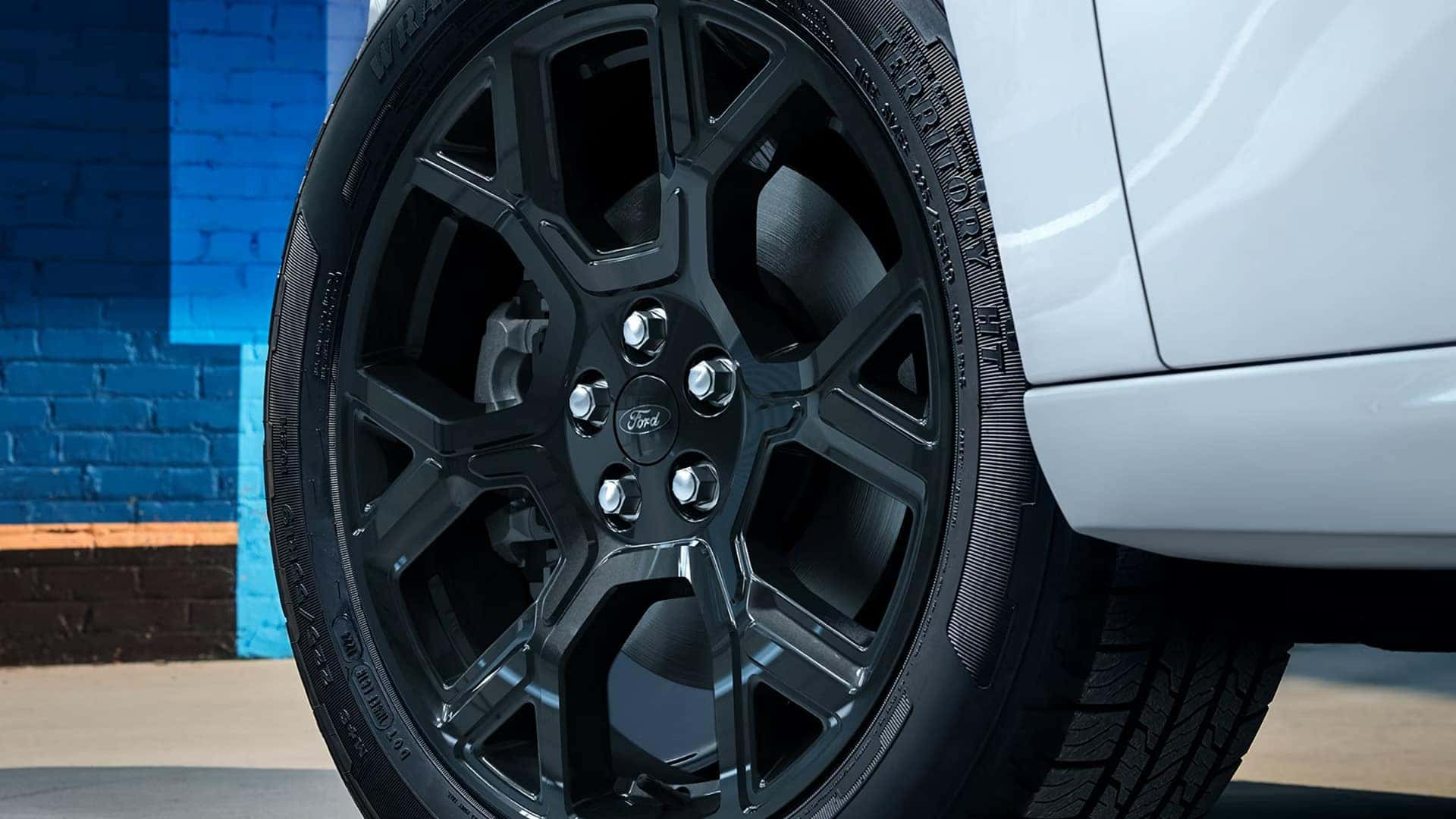 Close-up of a black alloy wheel and tire on a white 2026 Ford Maverick