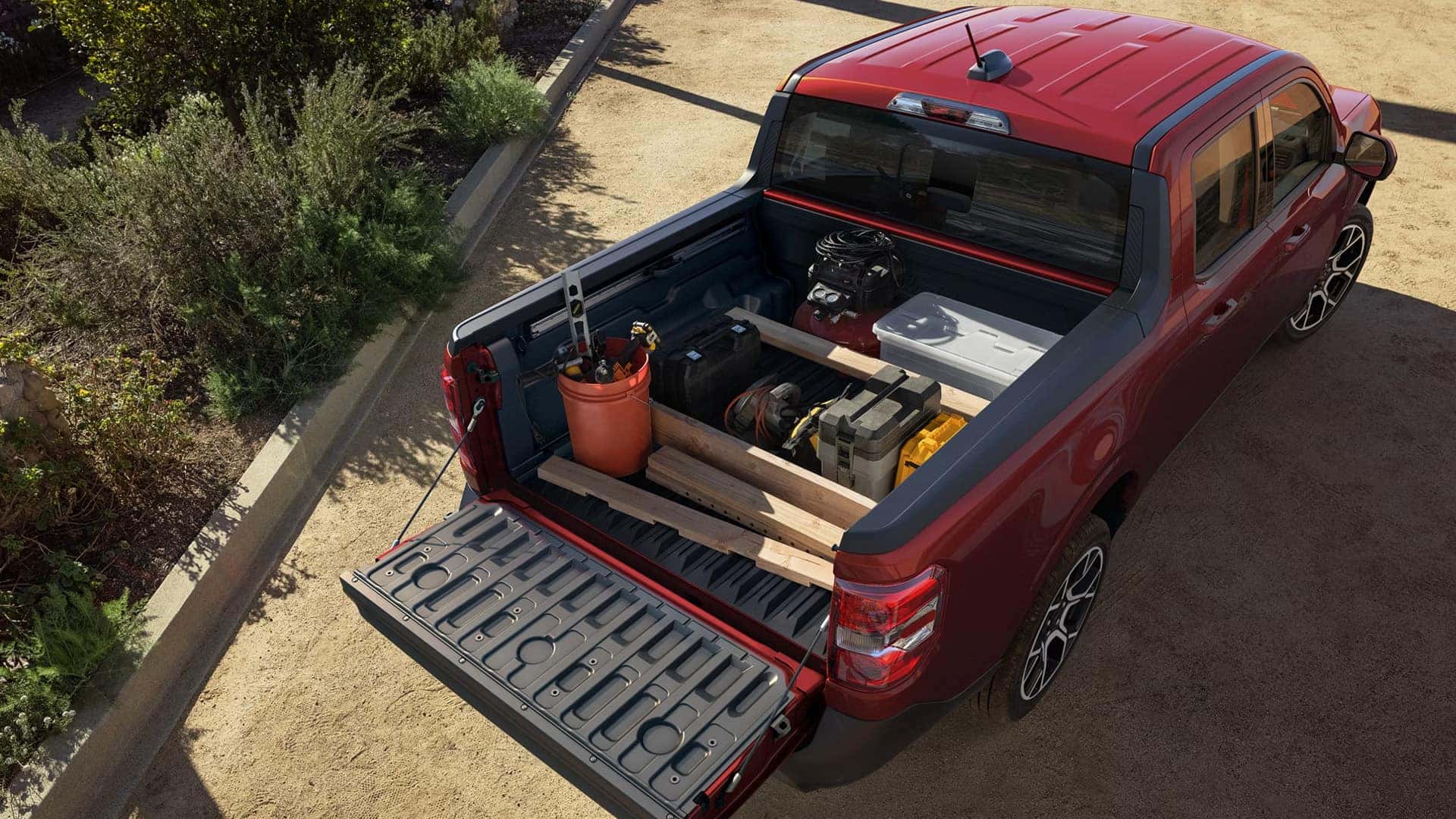 Open bed of a red 2026 Ford Maverick carrying tools and supplies in divided storage areas