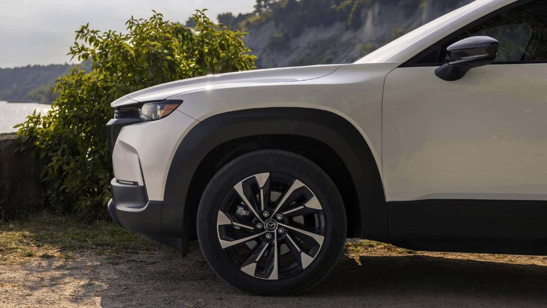 Close-up of the black and machine-finished alloy wheel on a white 2026 Mazda CX-50 Hybrid