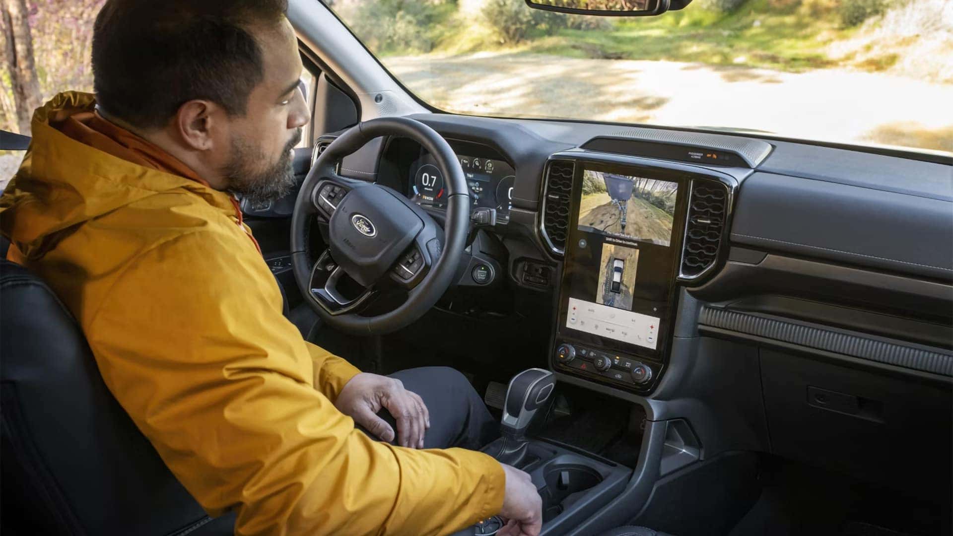 Driver using the center touchscreen and camera display inside a 2026 Ford Ranger