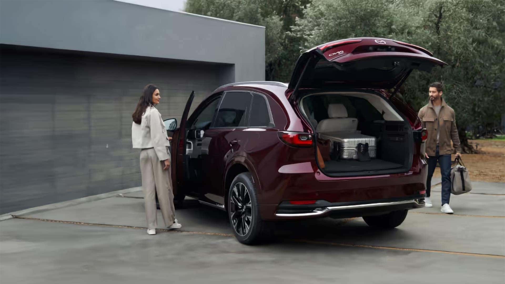 Red 2026 Mazda CX-90 PHEV with its rear power liftgate open and luggage in the cargo area