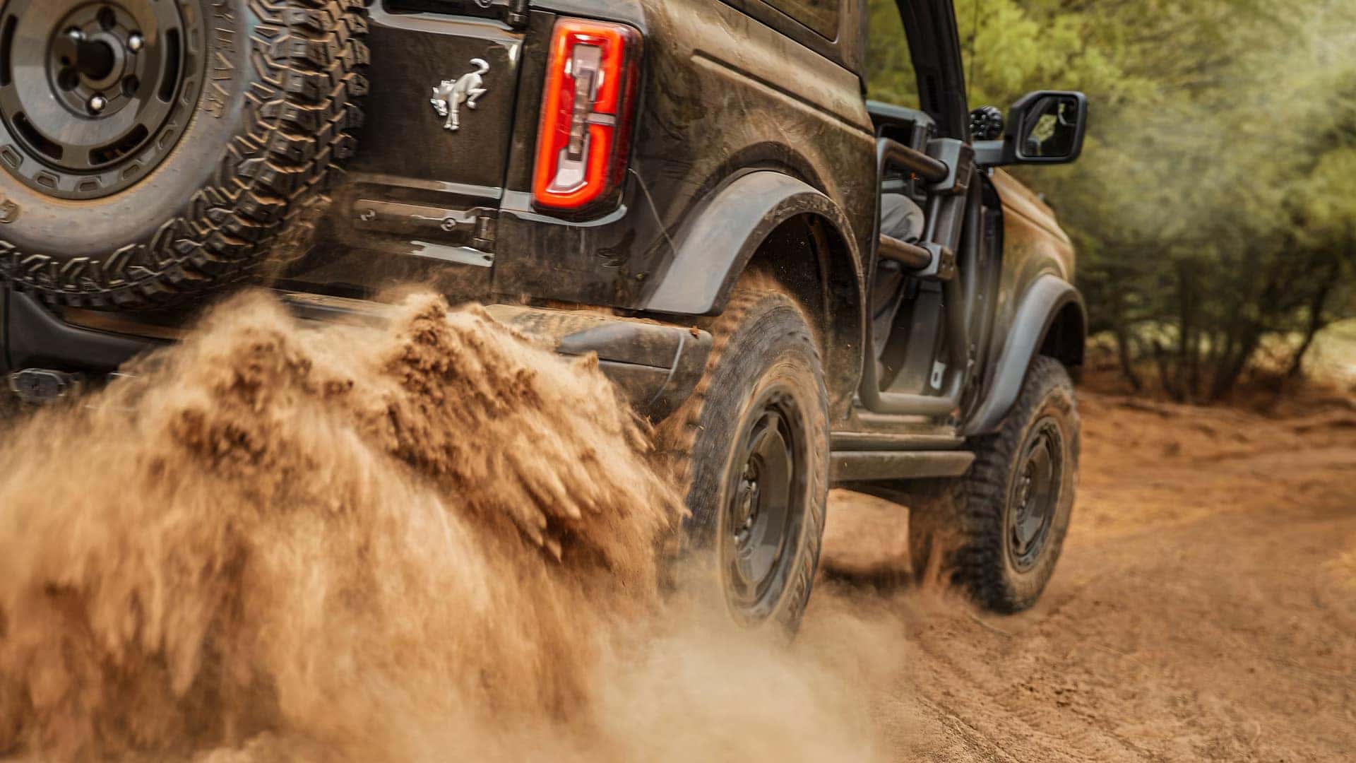 2026 Ford Bronco with removable doors kicking up sand while driving on an off-road trail