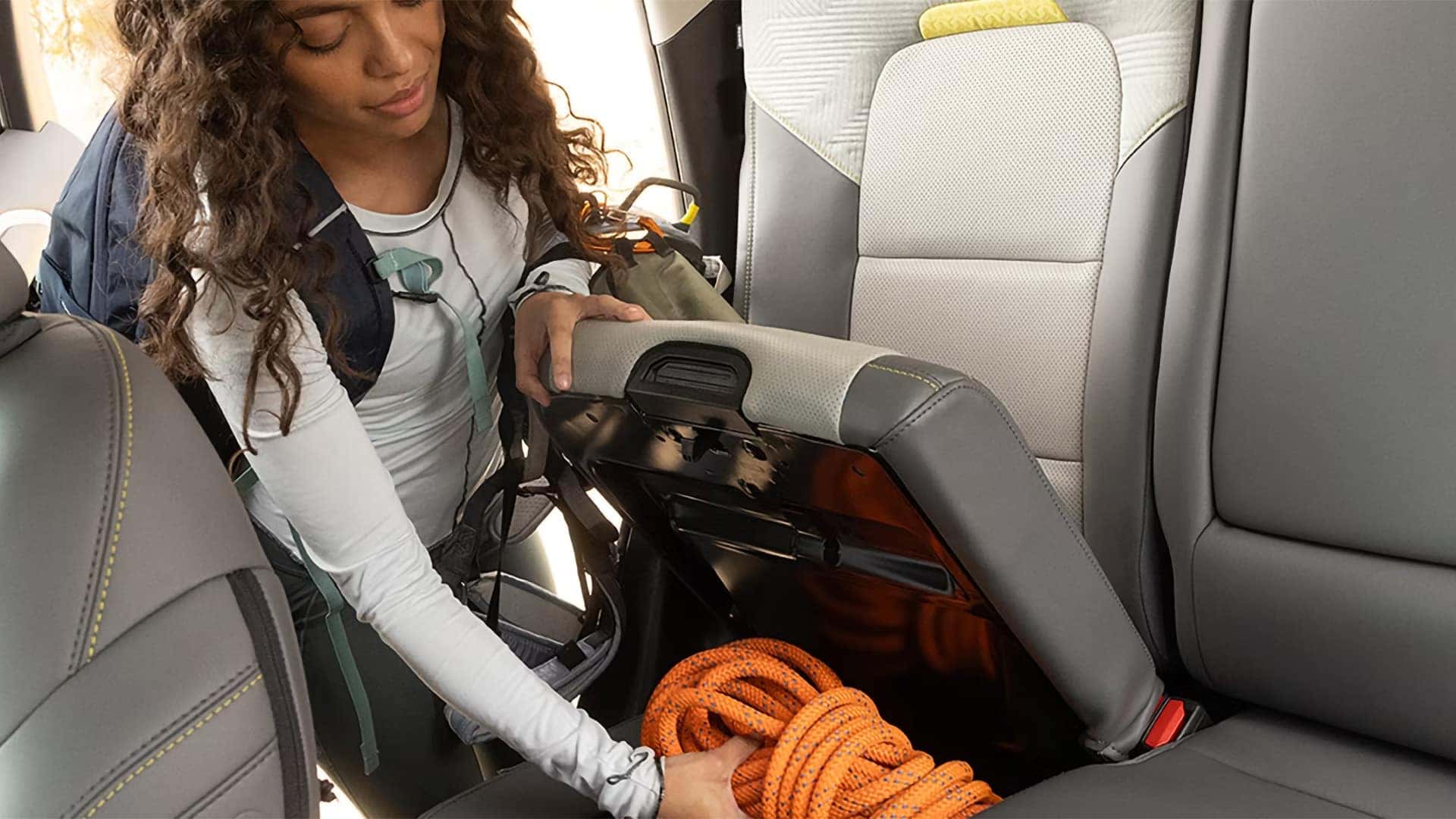 Person placing climbing rope in the under-seat storage compartment of a Ford Bronco Sport