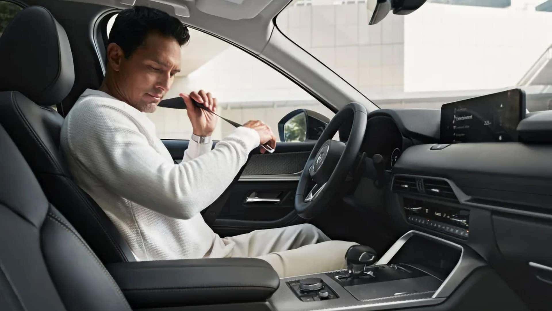 Driver fastening his seat belt inside the comfortable 2026 Mazda CX-70 PHEV cabin