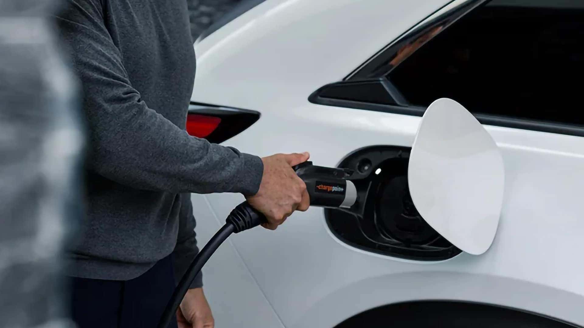 Driver connecting a charging cable to a white 2026 Mazda CX-90 PHEV