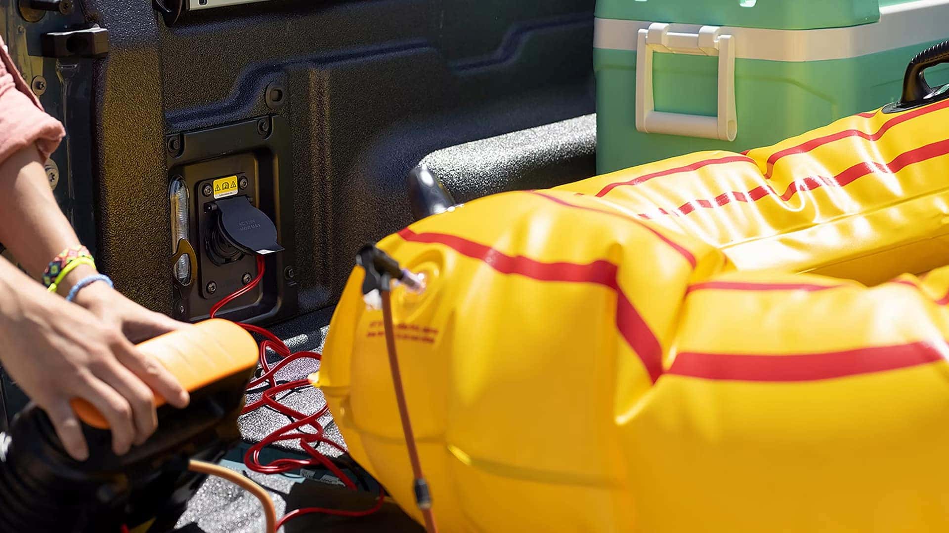Person using an air pump beside an inflatable raft in a Ford Maverick cargo bed