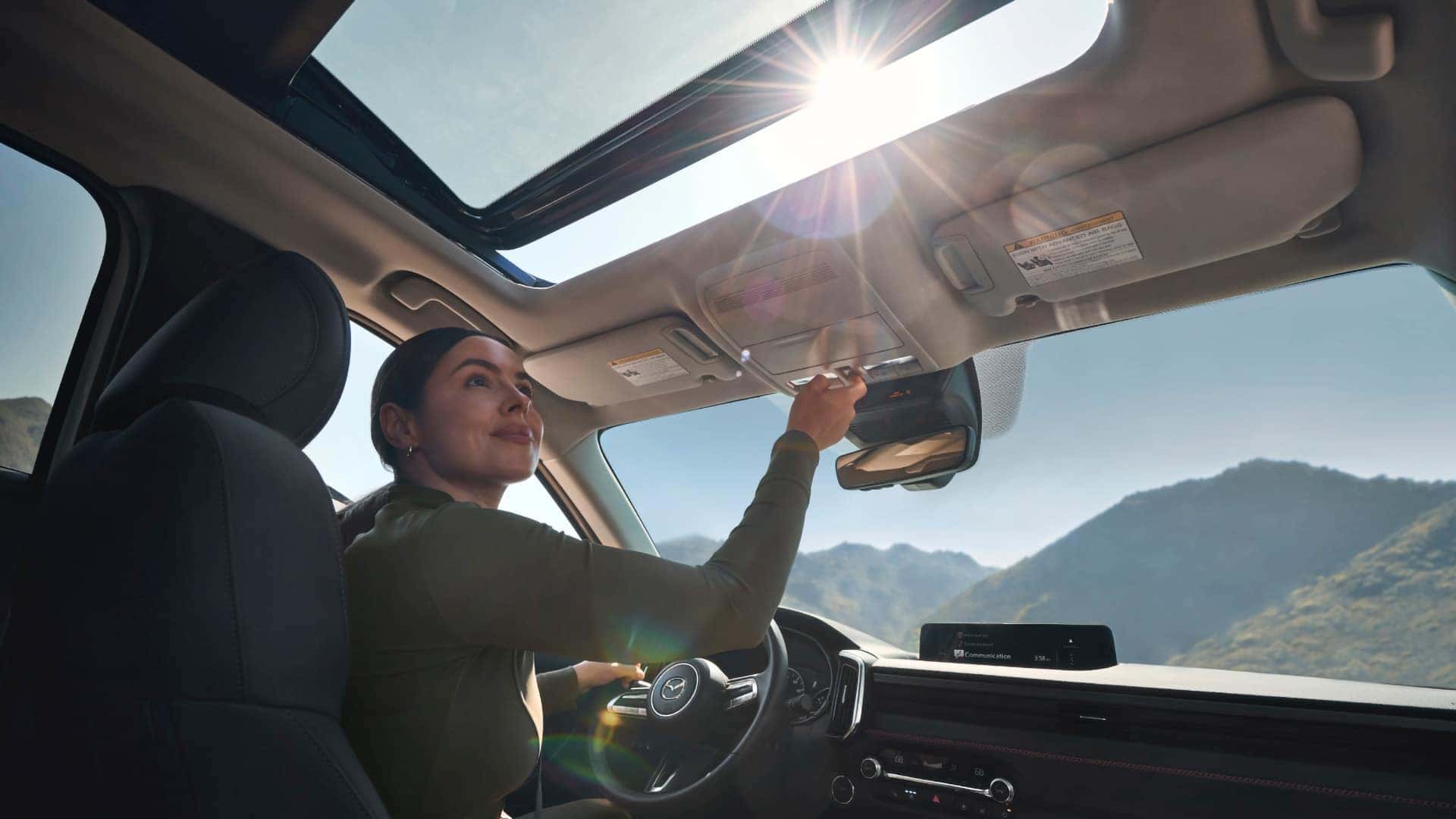 Driver opening the panoramic moonroof inside the 2026 Mazda CX-50 Hybrid