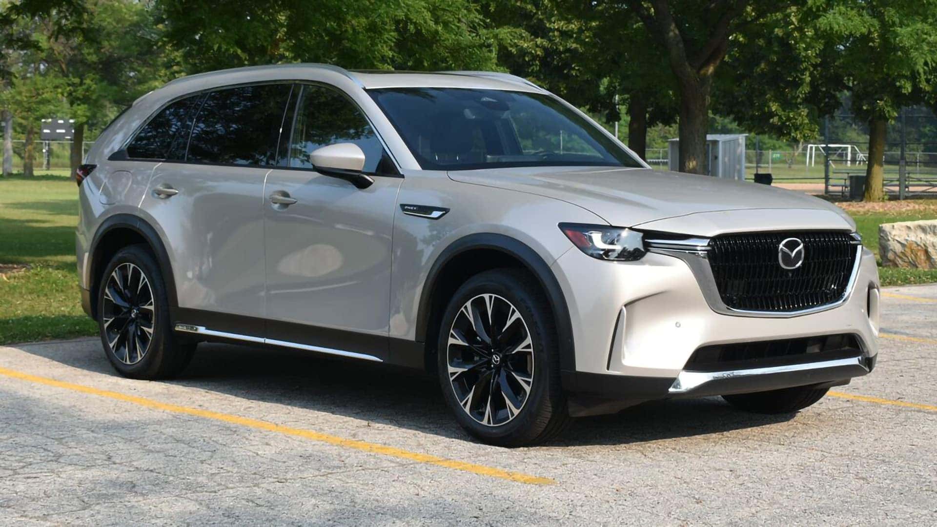 Light metallic 2026 Mazda CX-90 PHEV in front three-quarter view near a park