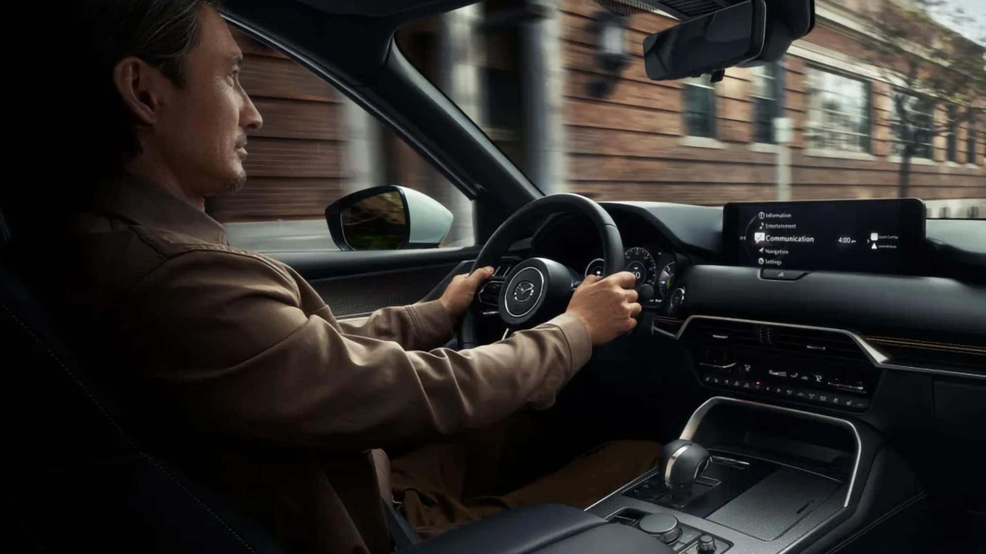 Driver inside a 2026 Mazda CX-90 PHEV using the cockpit with the Mazda Connect display visible