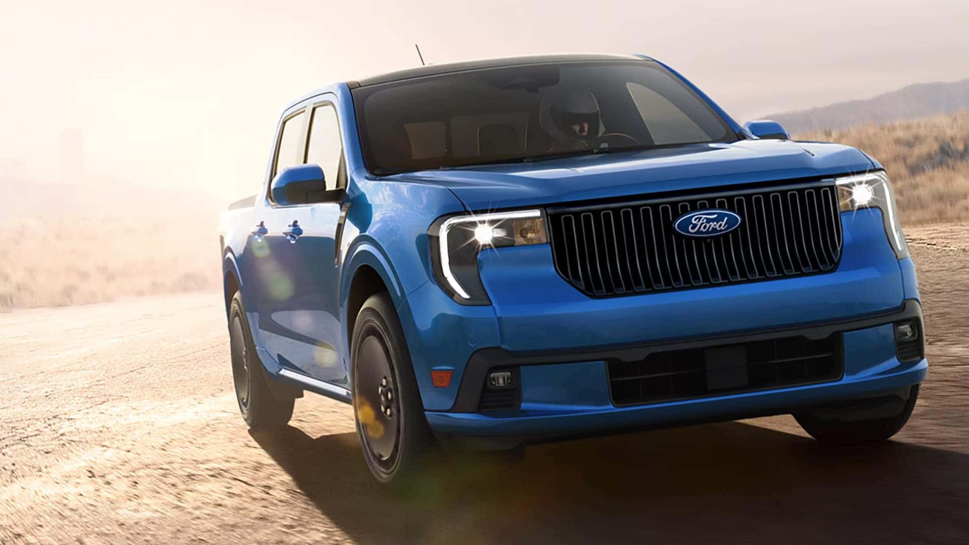 Blue 2026 Ford Maverick driving on a sunlit road, viewed from the front
