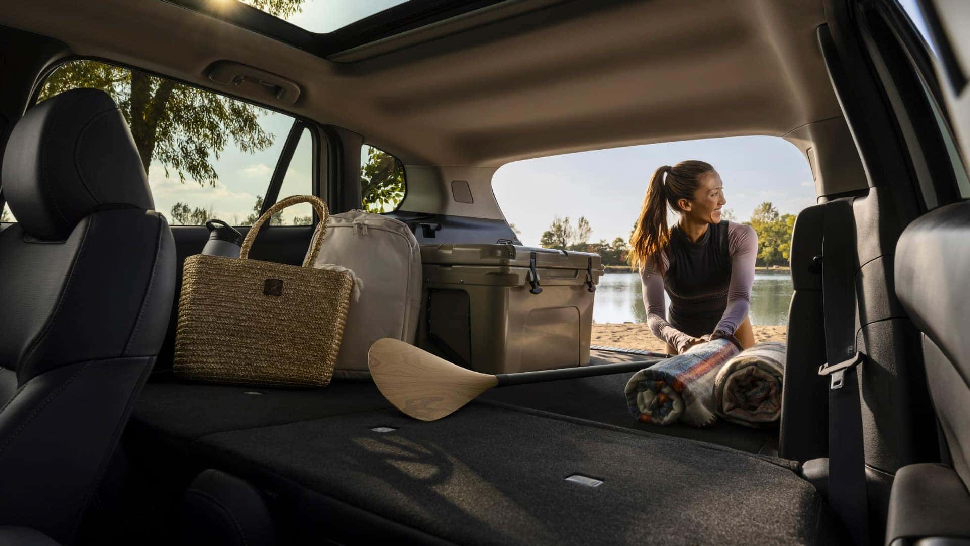 2026 Mazda CX-50 Hybrid cargo area with folded rear seats, luggage, cooler, and paddle
