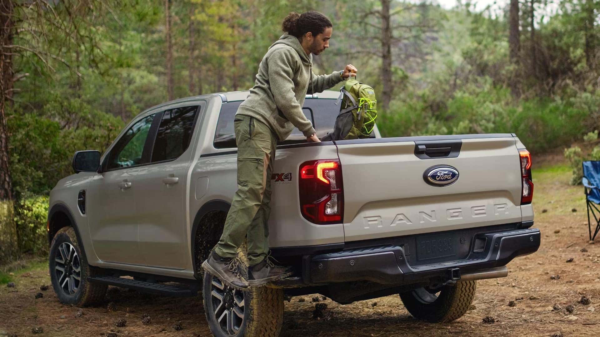 White 2026 Ford Ranger 4x4 parked at a campsite with a person loading gear into the bed