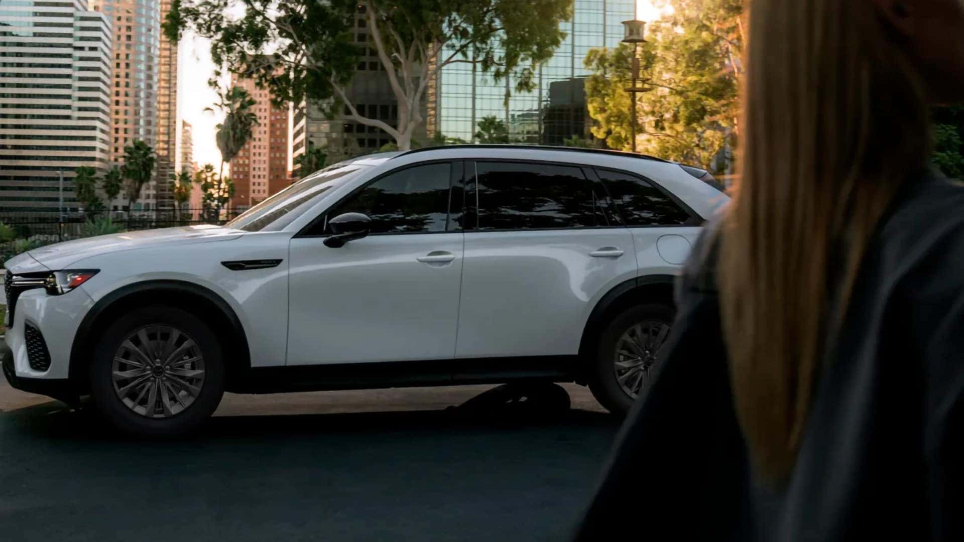 White 2026 Mazda CX-70 PHEV shown in profile near downtown buildings