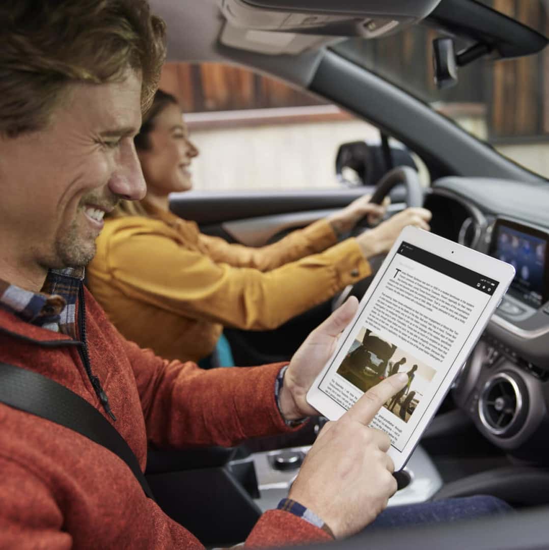 Interior view of a man using a tablet in the passenger seat of a 2026 Chevrolet Trailblazer LT with Jet Black interior.